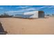 Expansive land featuring a metal shed and solar panels under a bright blue sky at 1612 N 201St Ave, Buckeye, AZ 85396