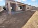 An exterior view of backyard with a covered patio, windows, and a blank canvas for landscaping at 16472 W Tether Trl, Surprise, AZ 85387