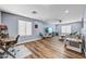 Bright living room features wood floors, neutral paint, a ceiling fan and a desk workspace at 16585 W Harrison St, Goodyear, AZ 85338