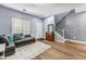 Inviting living room with wood floors and staircase, gray sofa, and natural light at 16585 W Harrison St, Goodyear, AZ 85338