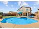 Backyard pool features a tanning ledge, blue umbrella, and lush landscaping at 16585 W Harrison St, Goodyear, AZ 85338