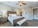 Spacious main bedroom featuring a ceiling fan, a bench, carpeted floor, and a dark brown, wooden bed frame at 1697 E Tangelo Pl, Queen Creek, AZ 85140