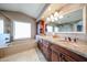 Bright bathroom featuring a soaking tub, granite countertop vanity with dual sinks, and cherry cabinetry at 17104 E Rand Dr, Fountain Hills, AZ 85268