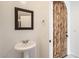 Hall bathroom with pedestal sink, decorative mirror, and natural wood door at 1750 E Ocotillo Rd # 11, Phoenix, AZ 85016