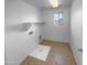 Functional laundry room featuring tile flooring, utility connections, shelving, and a window for natural light at 17699 W Tonto St, Goodyear, AZ 85338