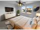 This bedroom has a ceiling fan, large windows, dresser, and neutral-toned rug at 17699 W Tonto St, Goodyear, AZ 85338