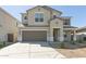 Two-story tan home featuring a two-car garage, neutral trim, and low-maintenance desert landscaping at 17712 W Hatcher Rd, Waddell, AZ 85355