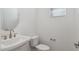 Powder room featuring a modern pedestal sink, toilet, and natural light at 17712 W Hatcher Rd, Waddell, AZ 85355