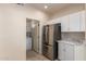 Efficient kitchen with stainless steel refrigerator, white cabinets, and adjacent laundry room at 19802 N Greenview Dr, Sun City West, AZ 85375