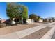 A single-story home features desert landscaping and a quaint tree-lined street at 221 N 151St Ave, Goodyear, AZ 85338