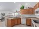 Well-lit kitchen with wooden cabinets, white appliances, and open view to the living room at 221 N 151St Ave, Goodyear, AZ 85338