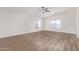 Well-lit bedroom with wood-look floors, a ceiling fan, and a window providing natural light and neighborhood views at 23407 W Ashleigh Marie Dr, Buckeye, AZ 85326