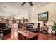 Spacious living room featuring hardwood floors, leather furniture, and an open layout connected to the kitchen at 24413 S Lakeway Sw Cir, Sun Lakes, AZ 85248