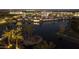 Aerial view of the community at night, featuring a lake with lit palm trees and well-lit buildings at 2777 W Queen Creek Rd # 13, Chandler, AZ 85248