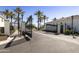 View of the property entrance gate surrounded by palm trees and white buildings against a bright blue sky at 2777 W Queen Creek Rd # 13, Chandler, AZ 85248