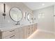 Modern bathroom with double vanity, round mirrors, stylish light fixtures, and wood cabinets at 3033 E Roma Ave, Phoenix, AZ 85016