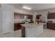 Well-lit kitchen boasts a granite island, stainless steel appliances and dark wood cabinetry at 30940 W Indianola Ave, Buckeye, AZ 85396