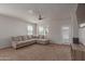 Comfortable living room with a sectional sofa, ceiling fan, and plenty of natural light from the window at 30940 W Indianola Ave, Buckeye, AZ 85396