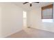 Bright bedroom boasts a ceiling fan, neutral carpet, and a window with woven shades at 34074 N Beeblossom Trl, San Tan Valley, AZ 85144