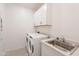 The laundry room features white appliances, white cabinets, and a stainless steel sink at 34074 N Beeblossom Trl, San Tan Valley, AZ 85144