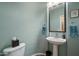 Well-lit powder room with a pedestal sink, framed mirror, and a charming, light blue painted wall at 35322 N 27Th Ln, Phoenix, AZ 85086