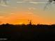 Scenic view of an orange sunsetting sky behind silhouette of rooftops and foliage at 35322 N 27Th Ln, Phoenix, AZ 85086