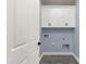 Cozy laundry room with ample white cabinets above a light blue wall and grey tile floors next to doorway at 3623 S 78Th Dr, Phoenix, AZ 85043