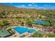 Stunning aerial view of the community pool and tennis courts with mountain views in Scottsdale, Arizona at 41012 N Noble Hawk Way, Anthem, AZ 85086