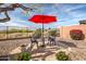 Charming backyard patio with a bistro set, bright red umbrella, and desert landscape at 41012 N Noble Hawk Way, Anthem, AZ 85086