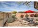 Secluded backyard patio with a bistro set, and desert landscaping under a bright blue sky at 41012 N Noble Hawk Way, Anthem, AZ 85086