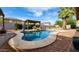 Backyard pool area featuring a covered patio, seating, lush landscaping, clear blue sky and desert foliage at 4312 W Olney Ave, Laveen, AZ 85339