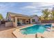 Backyard featuring swimming pool, covered patio with seating, and desert landscaping under blue sky at 43554 W Sunland Dr, Maricopa, AZ 85138