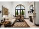 Bright living room with a fireplace, travertine floors, and an arched window overlooking the landscape at 5016 E Butler Dr, Paradise Valley, AZ 85253