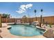 Private swimming pool with custom rock waterfall feature surrounded by beautiful desert landscaping and palm trees at 7712 N 54Th Ln, Glendale, AZ 85301