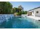 Backyard pool featuring a waterfall detail, set amid lush greenery for a private and serene outdoor experience at 8525 E Clarendon Ave, Scottsdale, AZ 85251