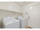 Bright laundry room features tile floors, an overhead shelf, a washer, and a dryer at 10814 W Alvarado Rd, Avondale, AZ 85392