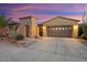 Charming single-story home with a stone accent wall, desert landscaping, a two-car garage, and a beautiful sunset backdrop at 12663 W Pinnacle Vista Dr, Peoria, AZ 85383
