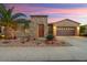 Charming single-story home with a stone accent wall, desert landscaping, a two-car garage, and a beautiful sunset backdrop at 12663 W Pinnacle Vista Dr, Peoria, AZ 85383