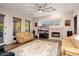 Spacious living room with a decorative fireplace, a ceiling fan, and lots of natural light at 12663 W Pinnacle Vista Dr, Peoria, AZ 85383