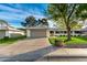 Inviting home with a large driveway, lush lawn, mature tree, and sidewalk access at 12703 W Shadow Hills Dr, Sun City West, AZ 85375