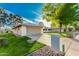 Home's exterior features a lush lawn, attached garage, and sidewalk at 12703 W Shadow Hills Dr, Sun City West, AZ 85375