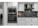 Contemporary kitchen boasting stainless steel appliances, black countertops, and white cabinetry at 12703 W Shadow Hills Dr, Sun City West, AZ 85375
