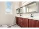 Bathroom featuring double sink vanity, dark cabinetry, and a large mirror at 15590 W Montecito Ave, Goodyear, AZ 85395