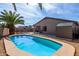 Backyard view features a sparkling pool with stone border, adjacent shed, and a lush palm tree, perfect for outdoor enjoyment at 16035 N 159Th Dr, Surprise, AZ 85374