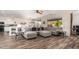 Open-concept living area with a large sectional sofa, wood-look floors, and an abundance of natural light flowing from outside at 18813 N Summerbreeze Way, Surprise, AZ 85374