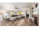 Spacious living room featuring wood flooring, a modern sectional sofa, and a cozy fireplace, perfect for relaxing and entertaining at 18813 N Summerbreeze Way, Surprise, AZ 85374