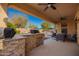 Covered patio featuring an outdoor kitchen and seating area overlooking the backyard at 18813 N Summerbreeze Way, Surprise, AZ 85374