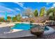 Backyard pool with rock features, desert landscaping, a tanning shelf, and waterfall at 18813 N Summerbreeze Way, Surprise, AZ 85374