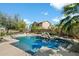 Custom pool features rock accents and integrated spa with lush tropical landscaping and mature trees at 3410 E Pageant Pl, Gilbert, AZ 85297