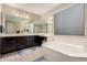 Spacious bathroom featuring dual sinks, a garden tub, neutral tile flooring and dark wood cabinets at 3687 E Blue Spruce Ln, Gilbert, AZ 85298